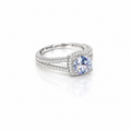 A silver-toned double-row halo ring featuring a round brilliant-cut blue sapphire center stone, set against a clean white background with a soft reflection.