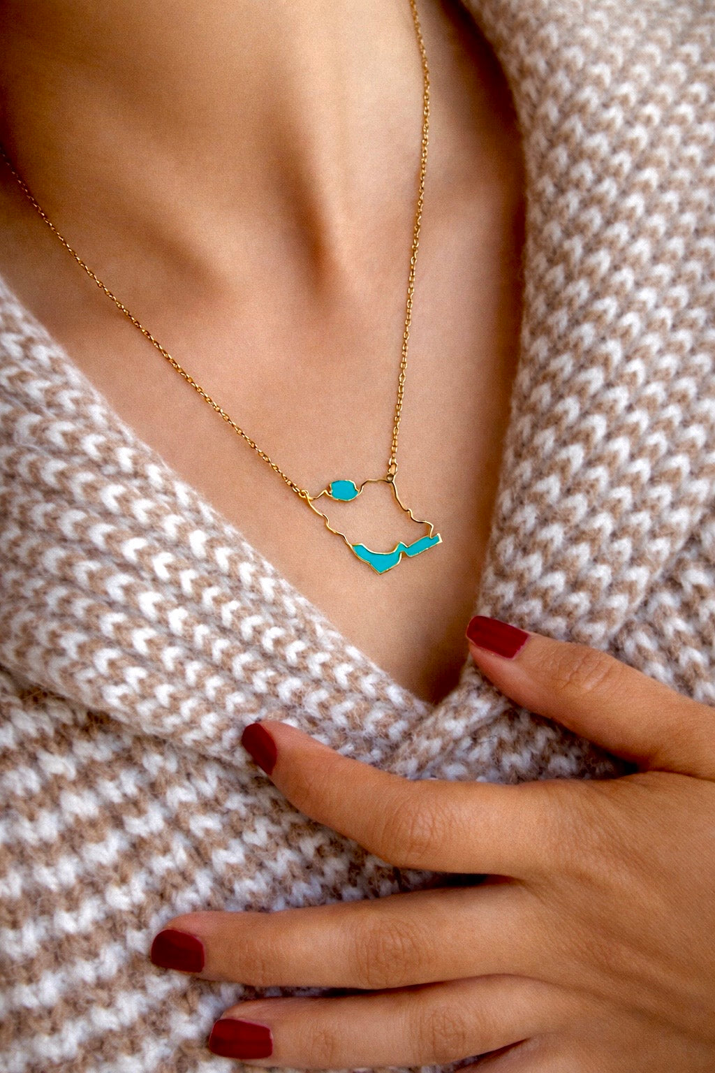 Necklace with Iran map pendants worn by a person in a textured garment.