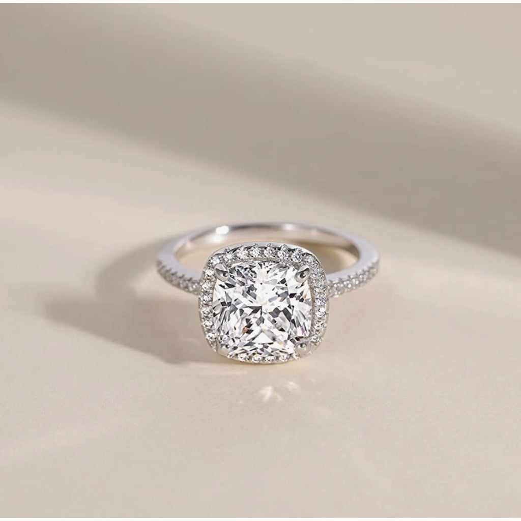 Diamond ring with a cushion-cut center stone on a beige background