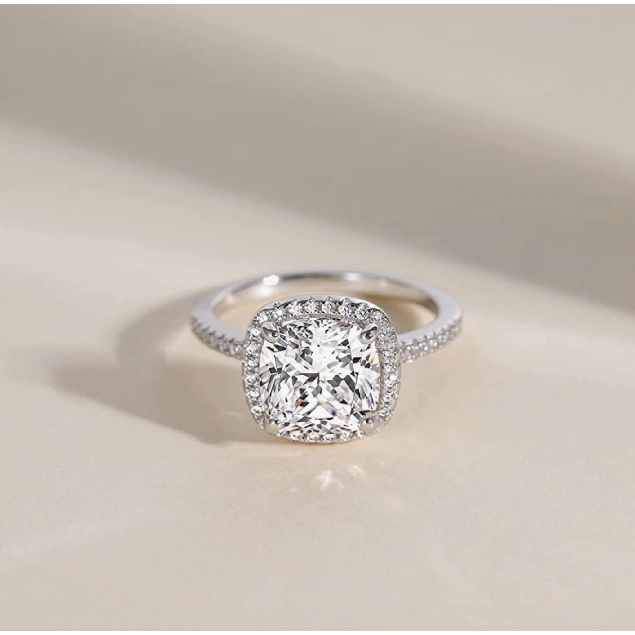 Diamond ring with a cushion-cut center stone on a beige background