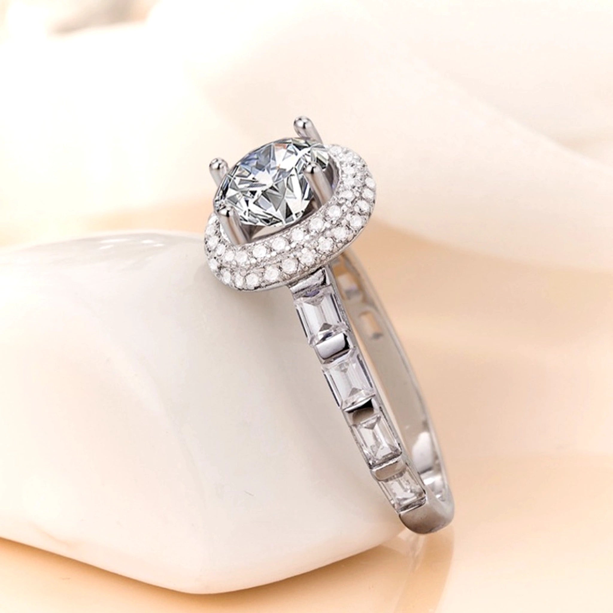 Silver ring with a large diamond and smaller diamonds on a soft beige background